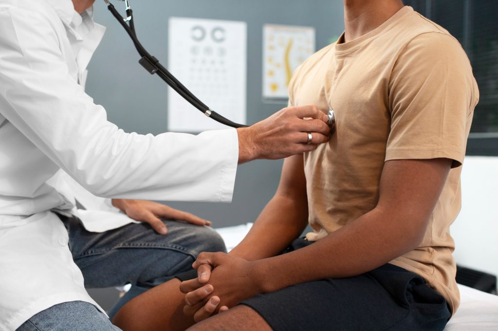 healthcare professional using a stethoscope and performing an executive health assessment to a patient 